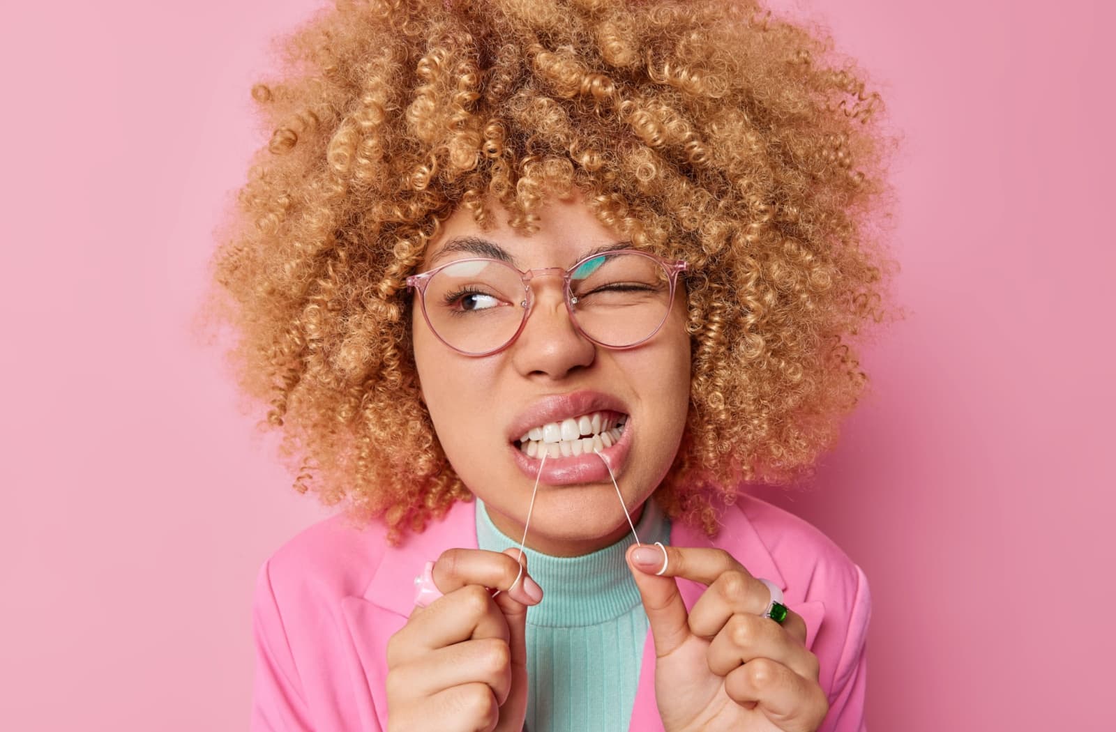 A person grits in pain as they floss their teeth.