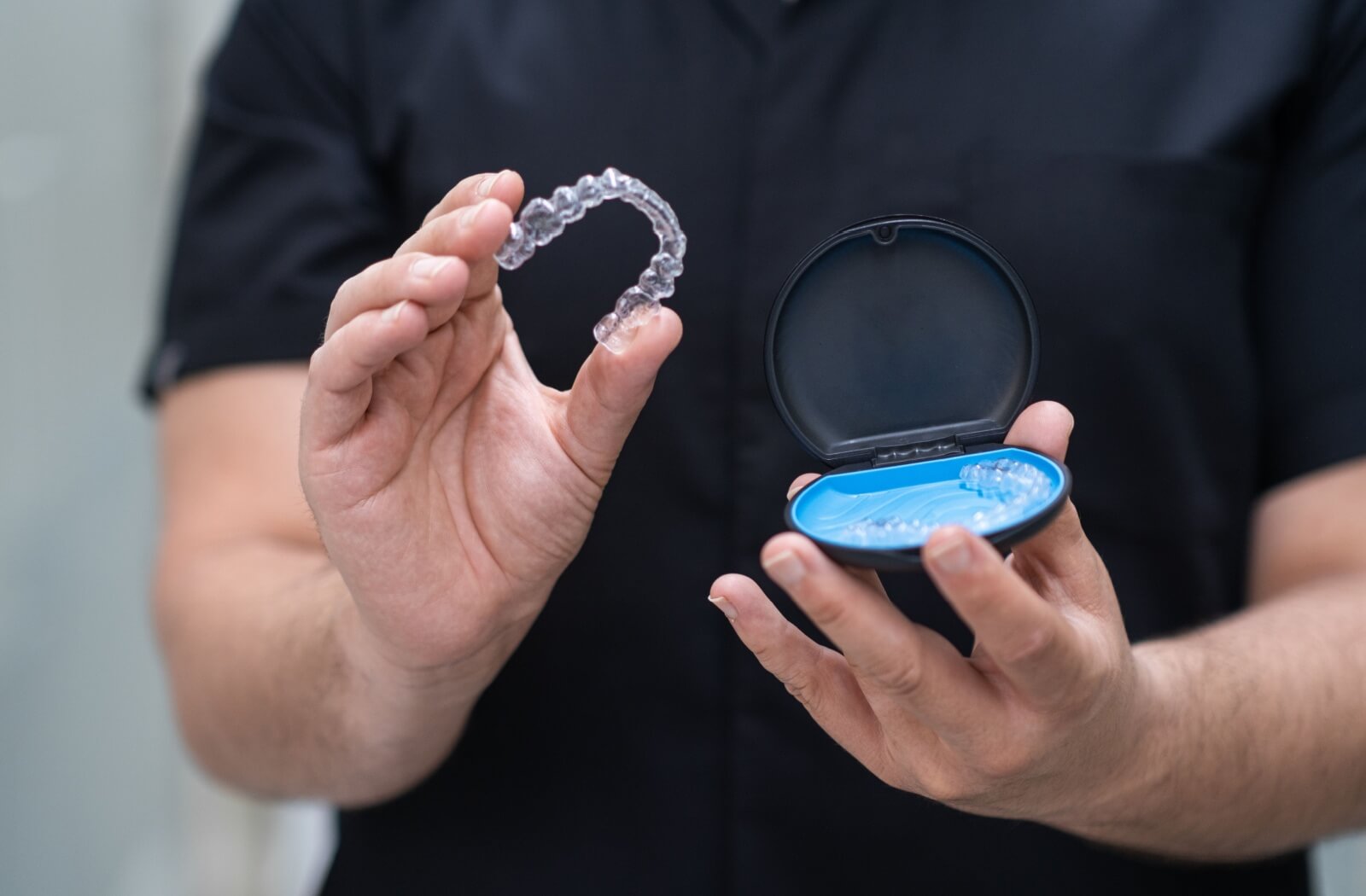 An orthodontist removes a clear aligner from its case and displays it