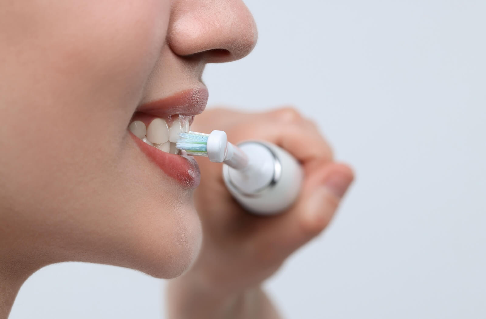 Close-up of a person using an electric toothbrush with clean, sparkling teeth